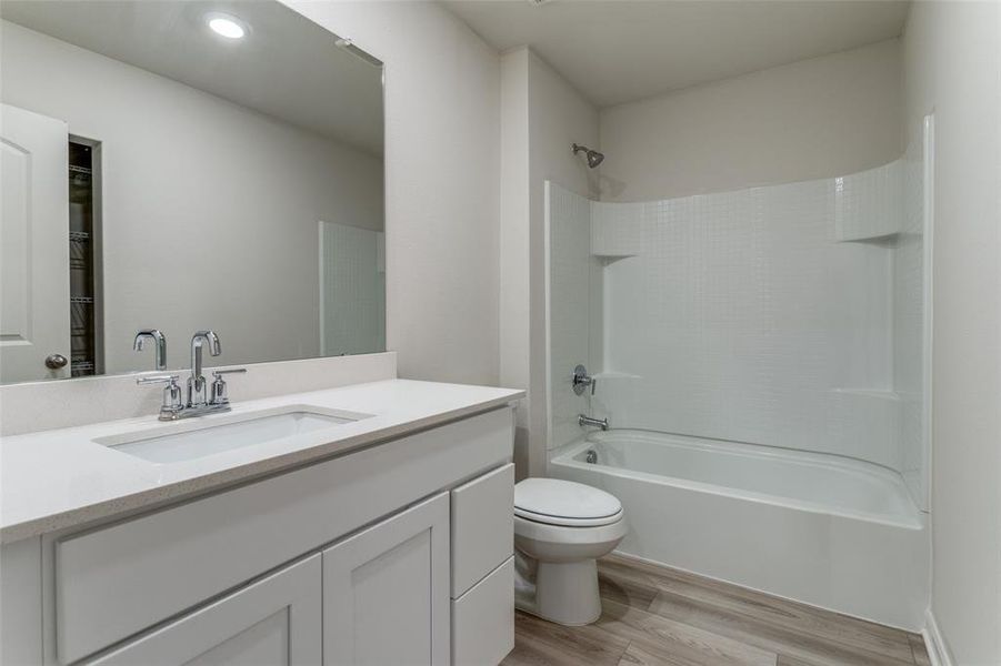 Full bathroom with hardwood / wood-style flooring, toilet, shower / bathtub combination, and vanity