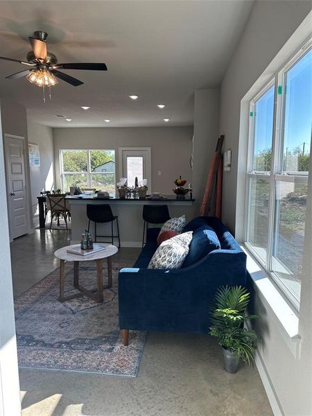 Living room featuring ceiling fan and concrete floors