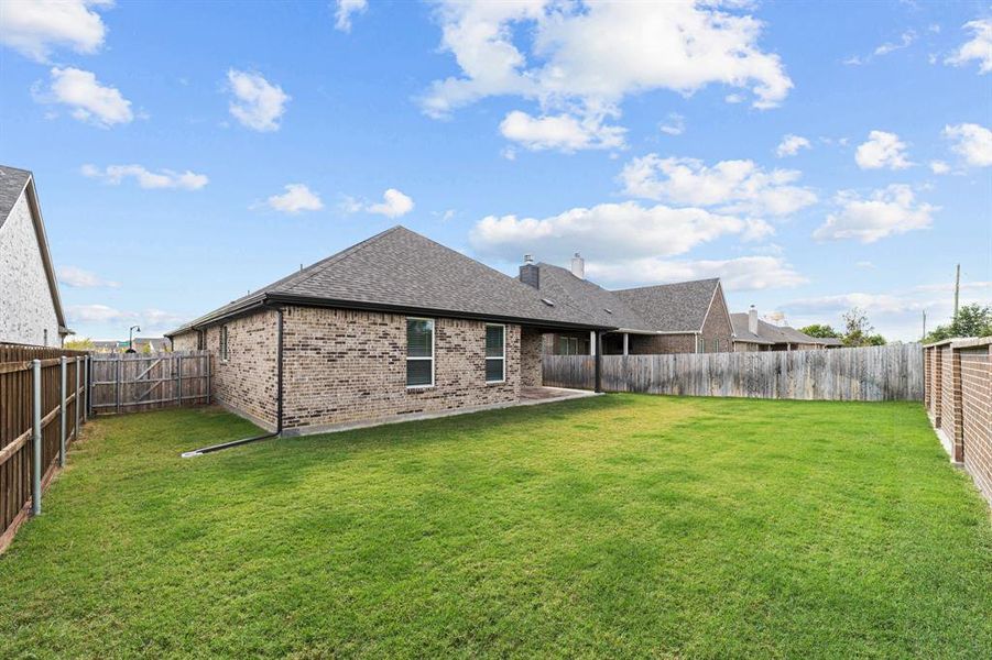 Back of property featuring a patio area and a lawn