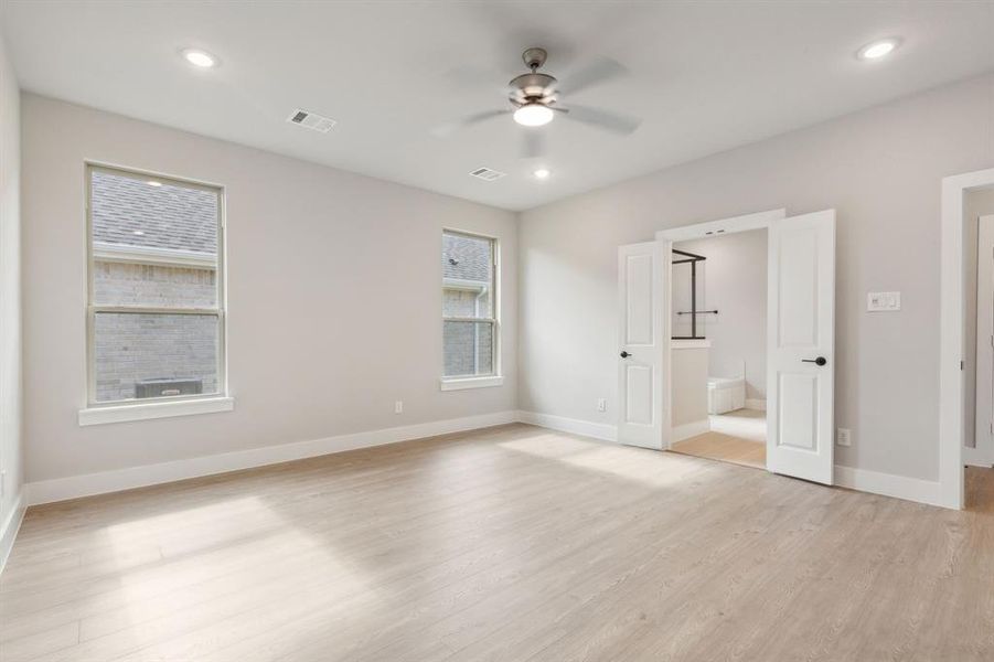 Unfurnished bedroom featuring light hardwood / wood-style flooring, connected bathroom, and ceiling fan