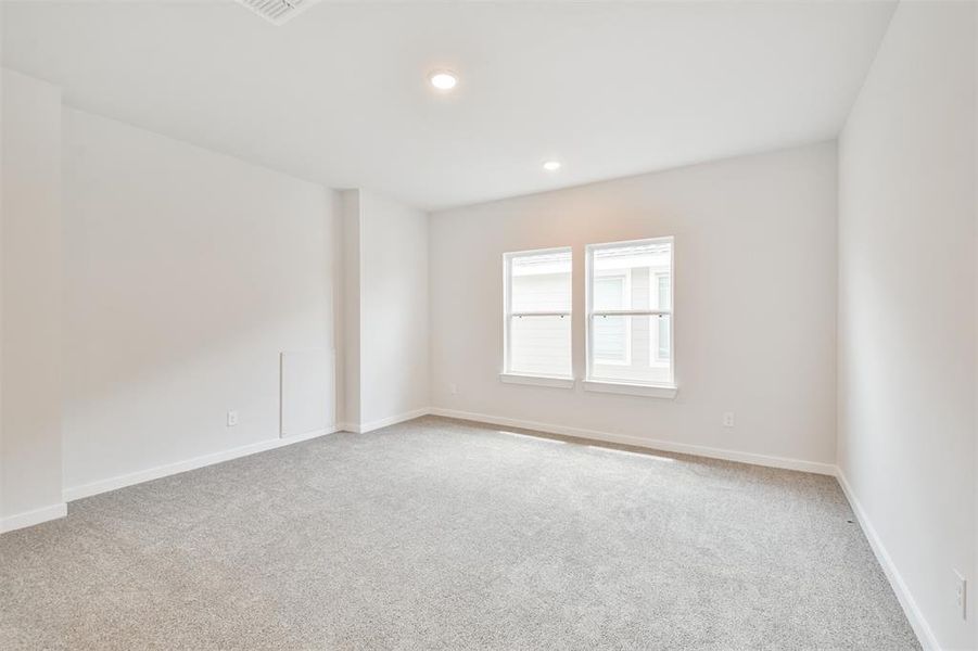 This is a bright, clean, and spacious room with neutral walls and carpet flooring, featuring a double window for natural light.