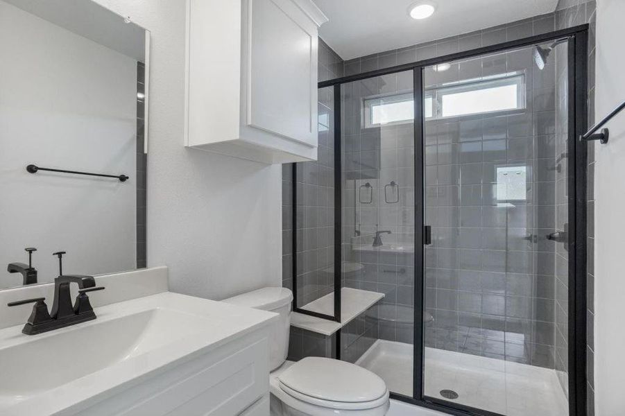 Bathroom with vanity, a shower with shower door, and toilet