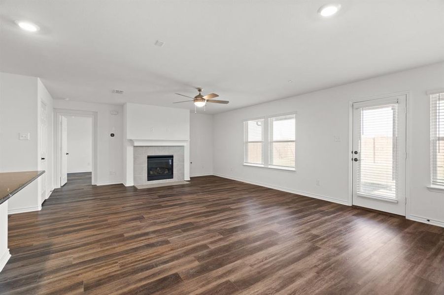 Unfurnished living room featuring a fireplace, ceiling fan, and dark hardwood / wood-style floors