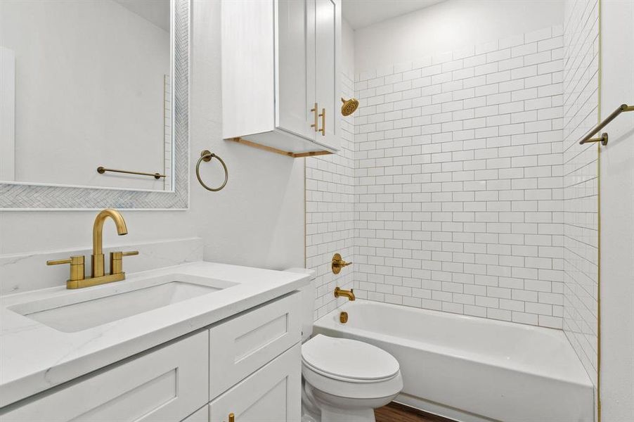 Full bathroom with tiled shower / bath, vanity, and toilet