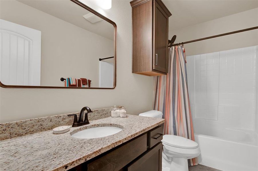 Secondary bathroom has built in cabinets and shower-tub combo.