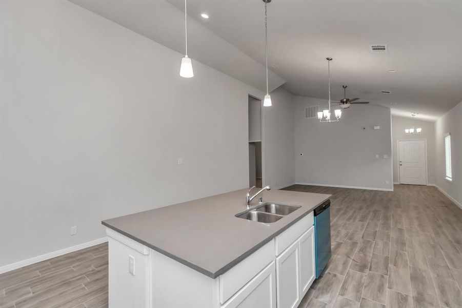 The heart of the home is this expansive kitchen island, complete with a dual sink and plenty of counter space. Overlooking the open living area, this island serves as the perfect spot for meal prep, casual dining, or gathering with loved ones. The pendant lighting and neutral tones add a modern touch to the space, making it as functional as it is beautiful. **This image is from another Saratoga Home - Wren floorplan.**