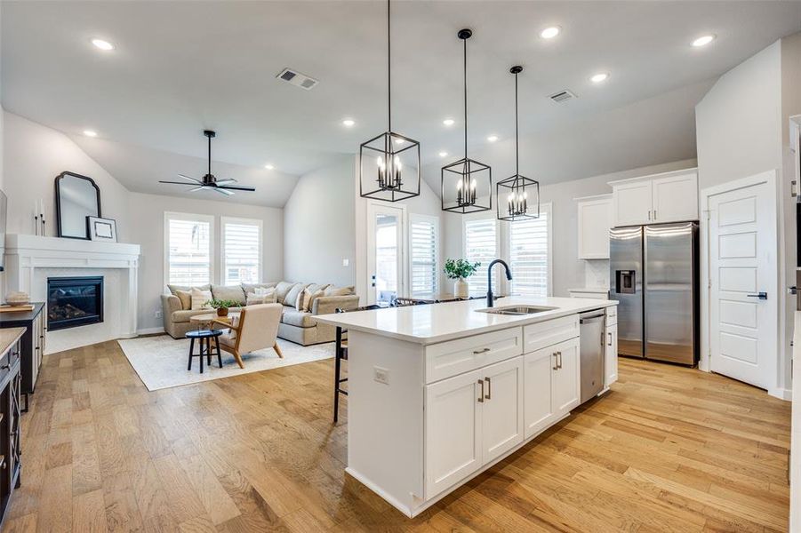 Kitchen featuring an island, lantern pendant lighting, stainless steel appliances, and white cabinetry