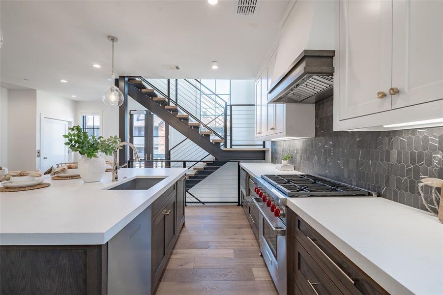 Kitchen featuring pendant lighting, sink, quartz countertops, Wolf range, and hardwood floors