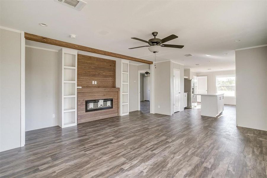 Unfurnished living room with crown molding, a multi sided fireplace, ceiling fan, and dark hardwood / wood-style floors