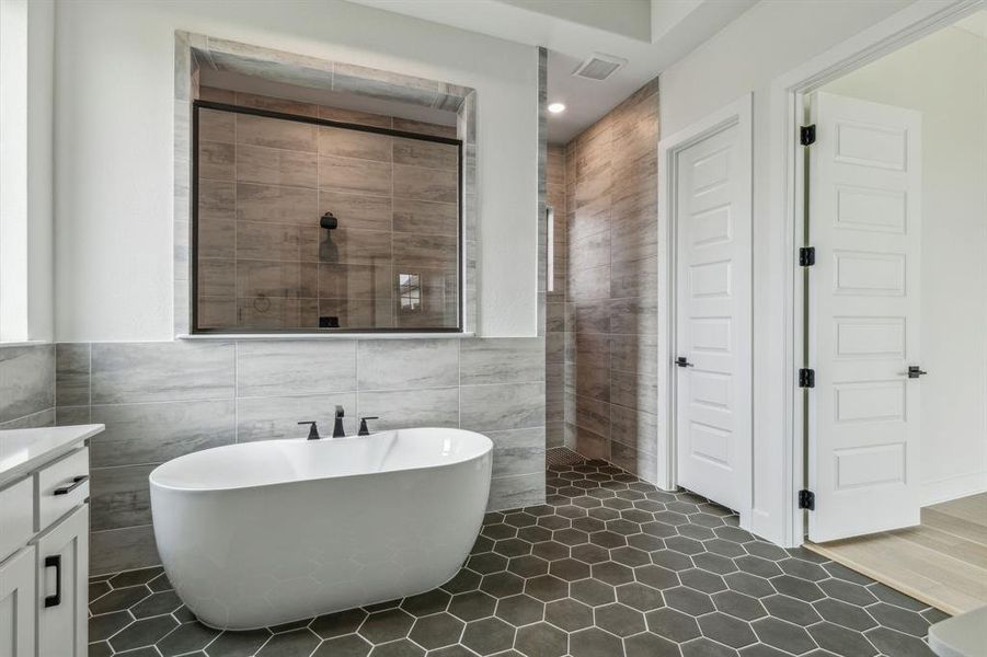 Bathroom with tile walls, vanity, and plus walk in shower