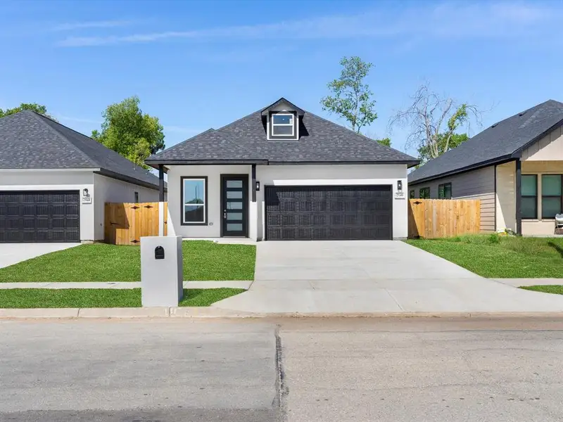 View of front of property featuring a front lawn and a garage