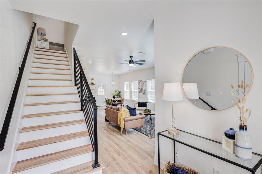 Staircase with light wood-type flooring and ceiling fan