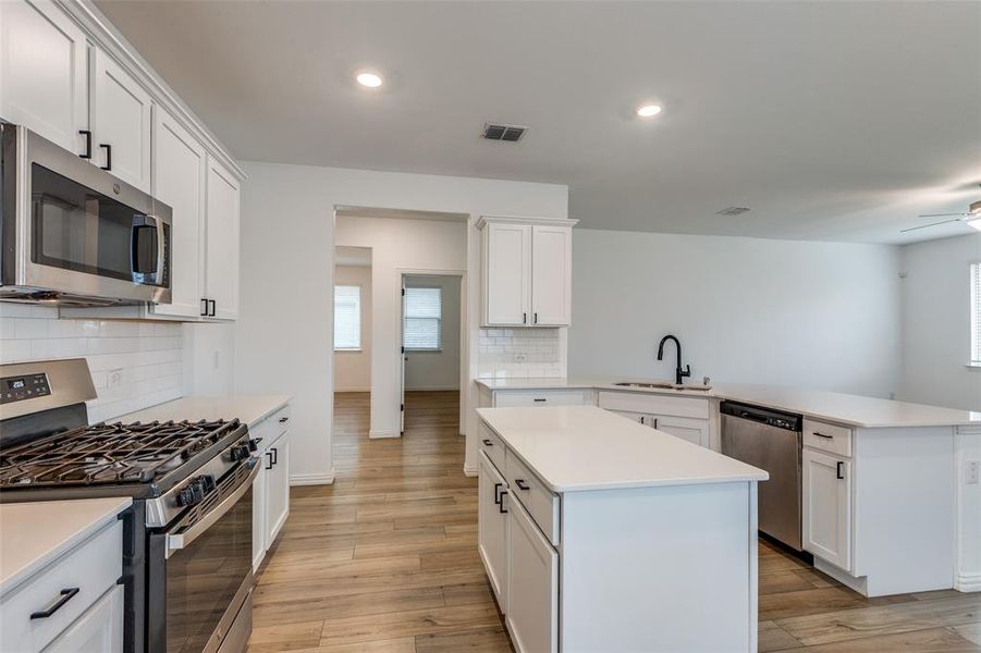 Kitchen featuring stainless steel appliances, sink, a kitchen island, and light hardwood / wood-style flooring