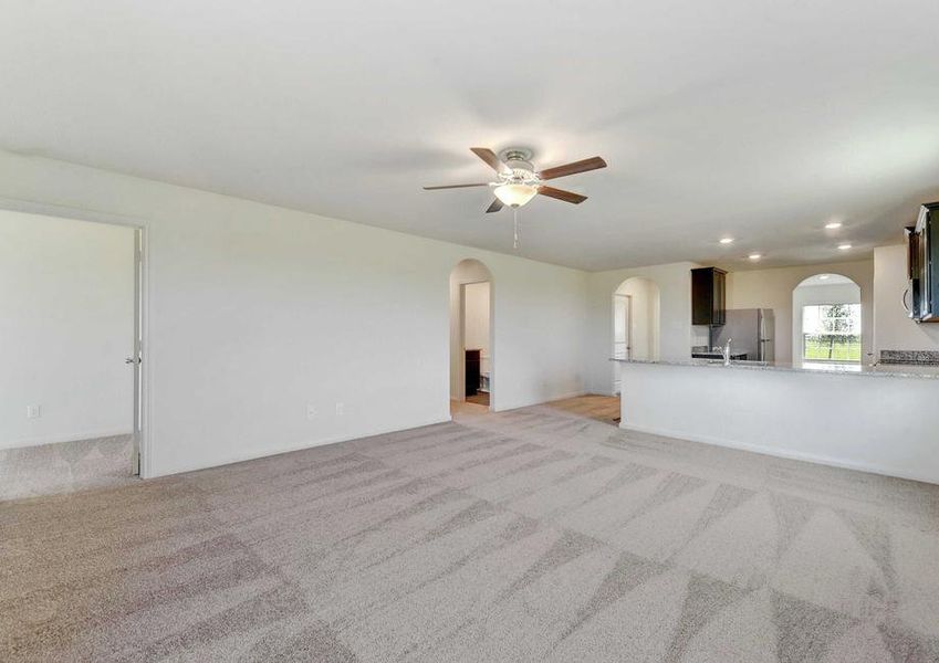 Frio great room with ceiling fan, carpeted flooring and view of kitchen and archways