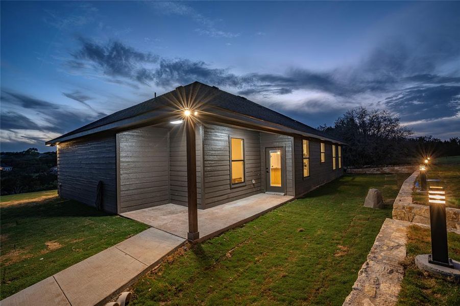 Property exterior at dusk with a lawn and a patio