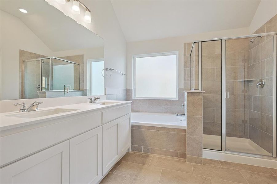 Bathroom featuring vanity, lofted ceiling, shower with separate bathtub, and tile patterned flooring