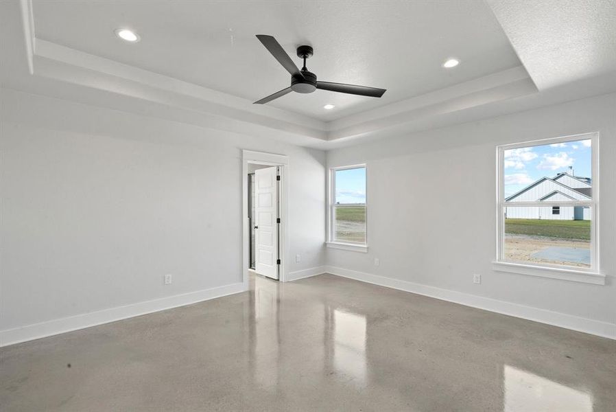 Primary room with concrete flooring, a tray ceiling, and a wealth of natural light