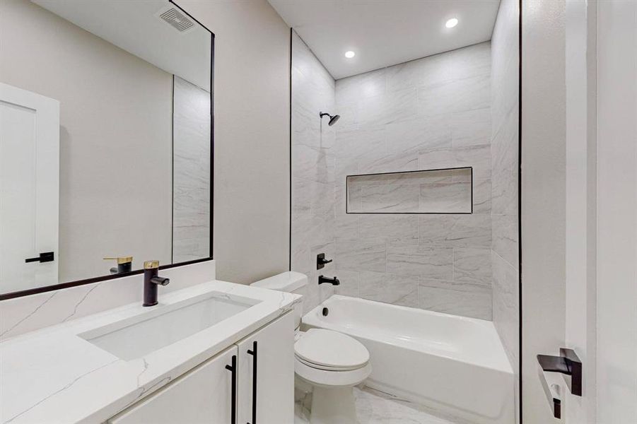 Full bathroom featuring tiled shower / bath, vanity, and toilet