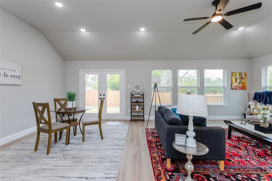 Living room featuring french doors, vaulted ceiling, light wood-type flooring, and ceiling fan