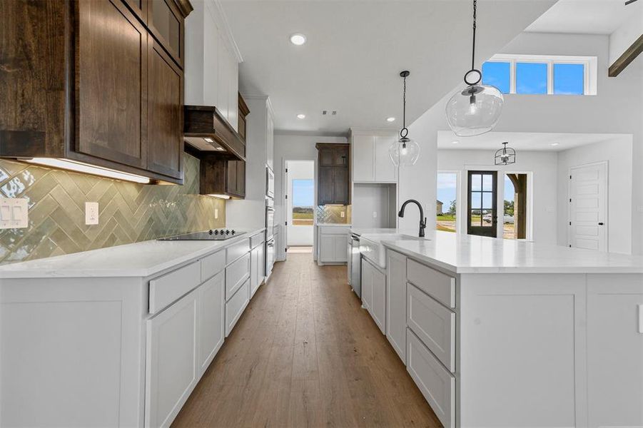 Kitchen with white cabinetry, a large island, tasteful backsplash, and light wood-type flooring