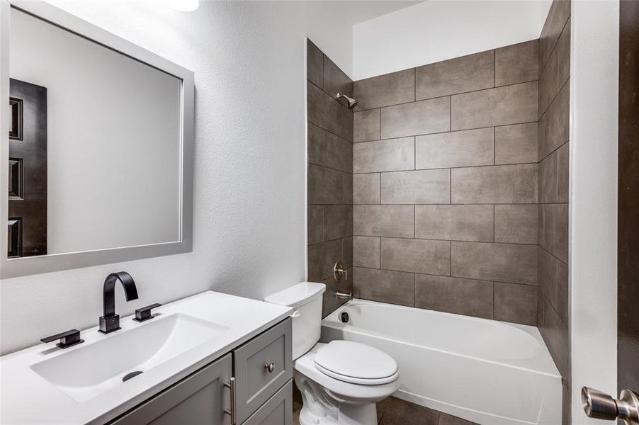 Full bathroom with tiled shower / bath, vanity, and toilet