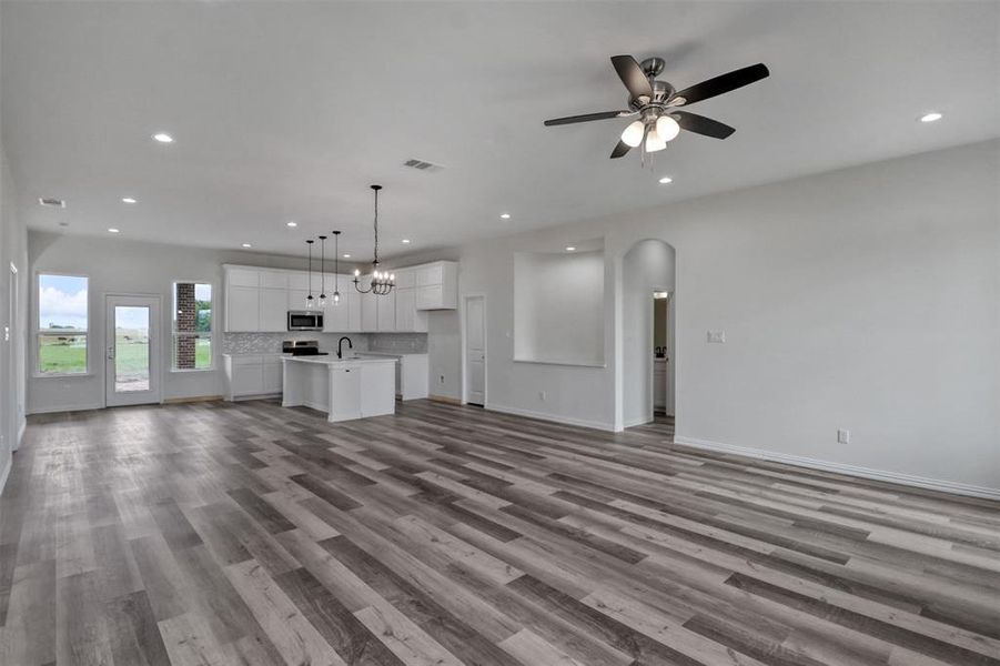 Unfurnished living room featuring ceiling fan with notable chandelier, light hardwood / wood-style flooring, and sink