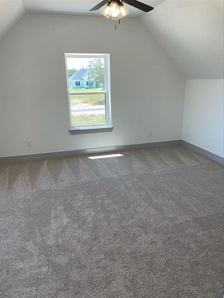 Bonus room with carpet floors, ceiling fan, and vaulted ceiling