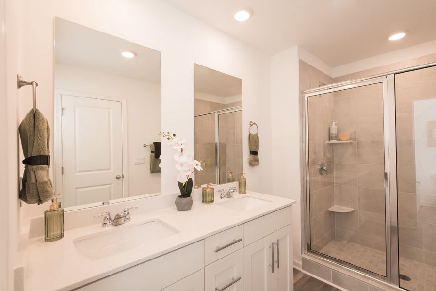 The primary bath features a walk-in shower and dual vanity sinks.