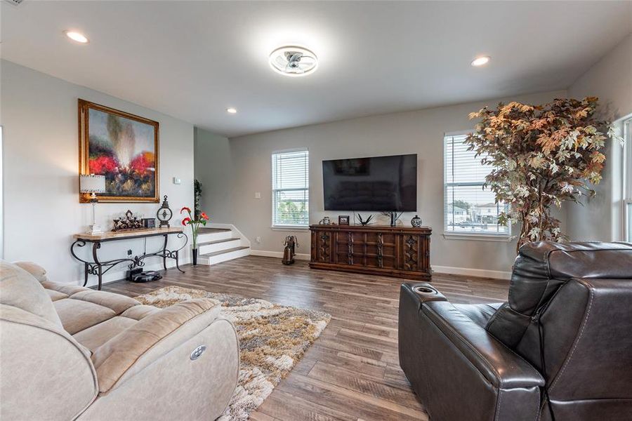 The living room exudes modern charm, featuring easy to maintain luxury vinyl plank flooring throughout and an inviting open layout that seamlessly connects to the dining and kitchen areas.