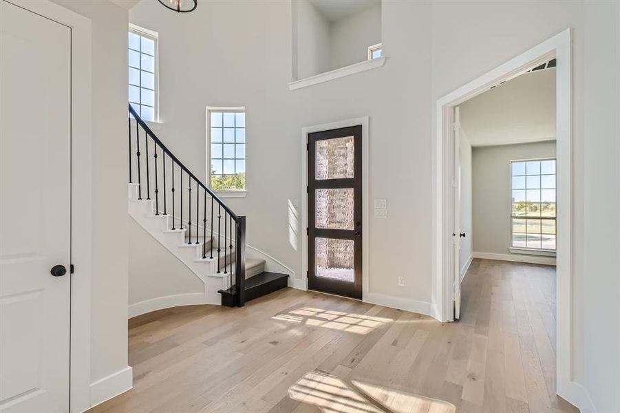 Foyer featuring a towering ceiling and light wood-type flooring