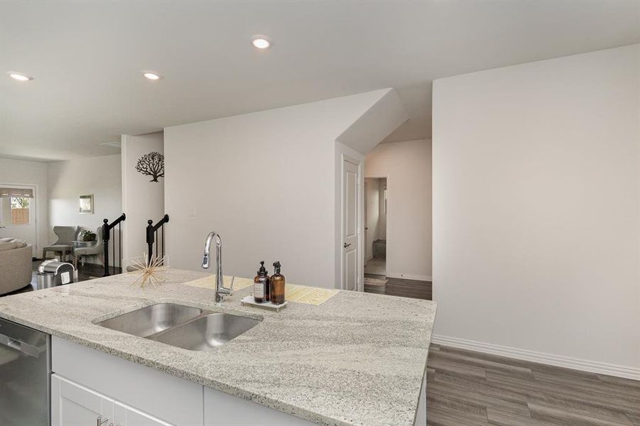 Kitchen with white cabinetry, sink, dark wood-type flooring, and light stone counters