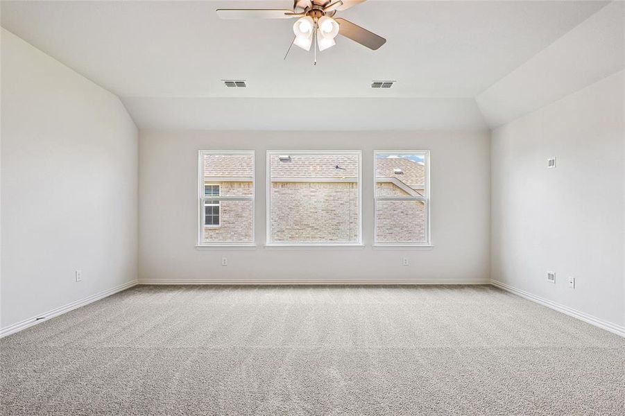 Unfurnished room featuring ceiling fan, light colored carpet, and vaulted ceiling