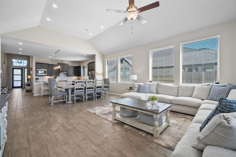 This living room is more like a GREAT room neutral paint, soaring high ceiling, recessed lighting, dark stained ceiling fan, and an amazing wall of windows providing a lovely view of your backyard.