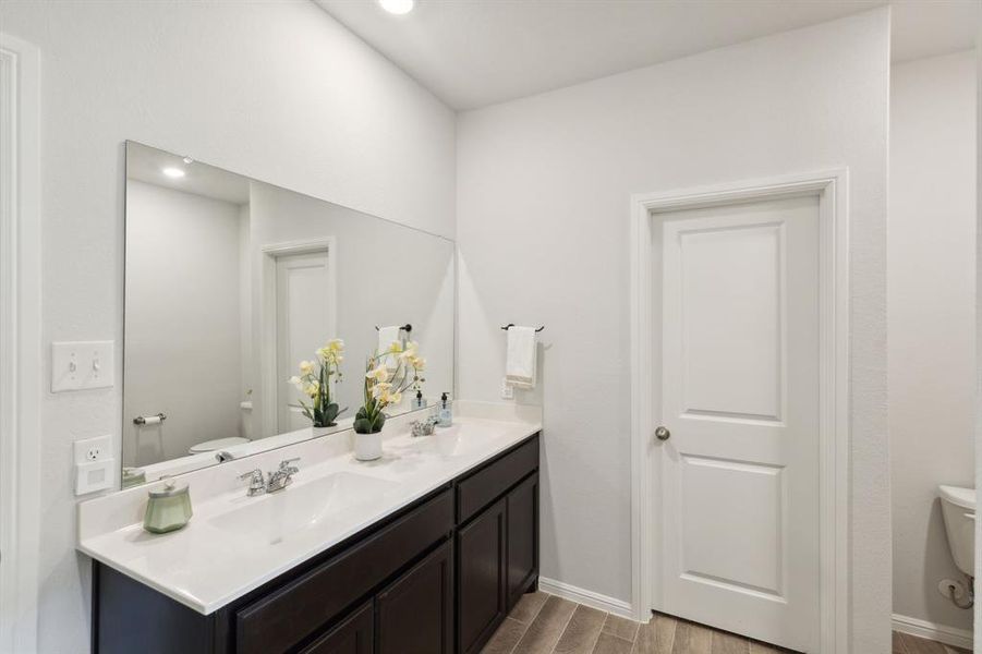 Bathroom featuring double sink vanity, hardwood / wood-style flooring, and toilet