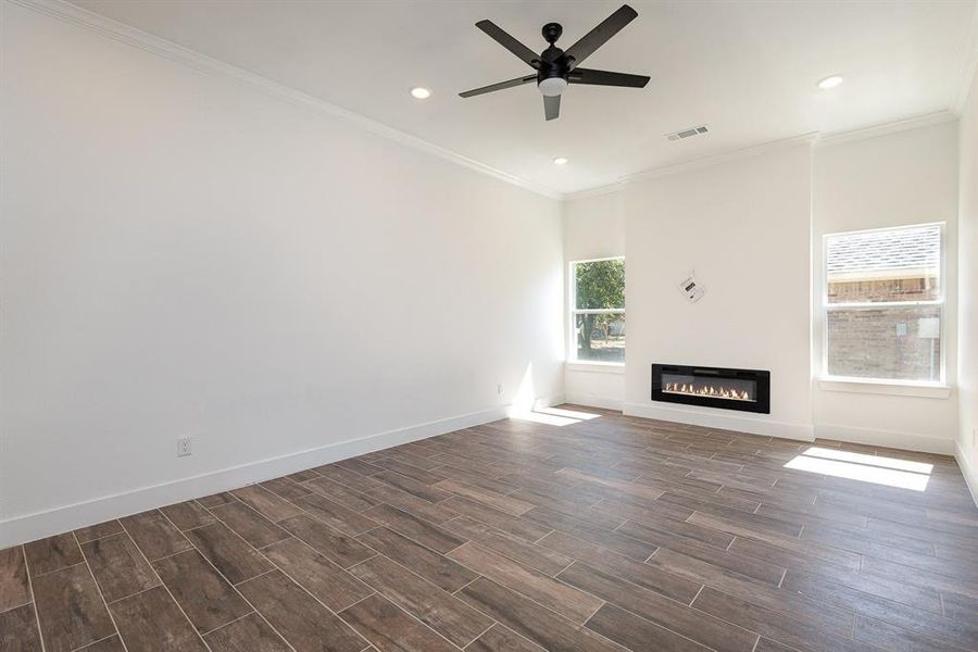 Unfurnished living room with crown molding, dark hardwood / wood-style floors, and ceiling fan