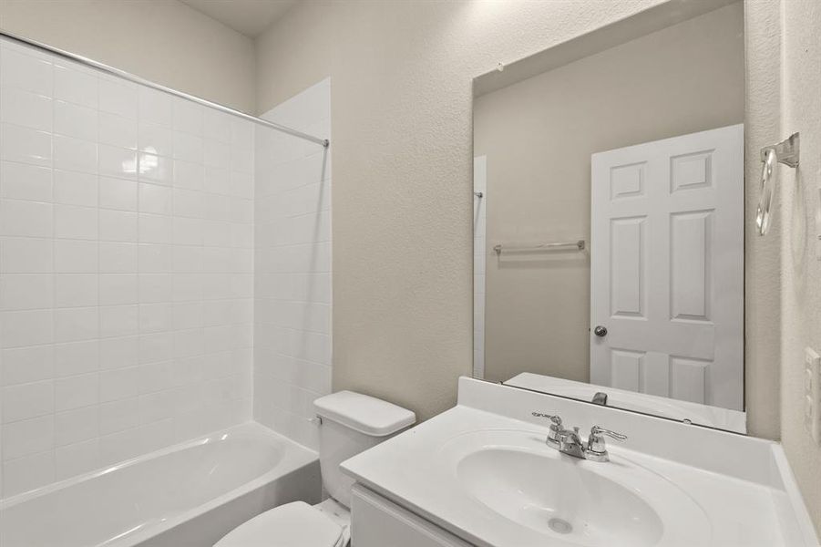 The secondary bath features tile flooring, white cabinetry and light countertops and a shower/tub combo. Perfect for accommodating any visiting family and friends.