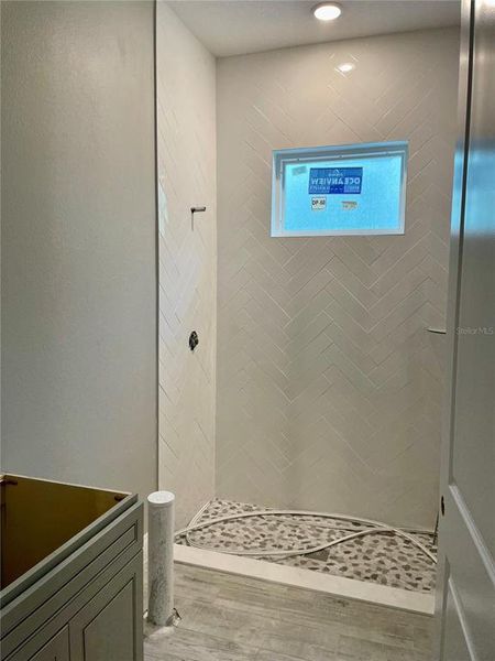 Full bath accessible to the lanai. Herringbone pattern tiled to the ceiling.