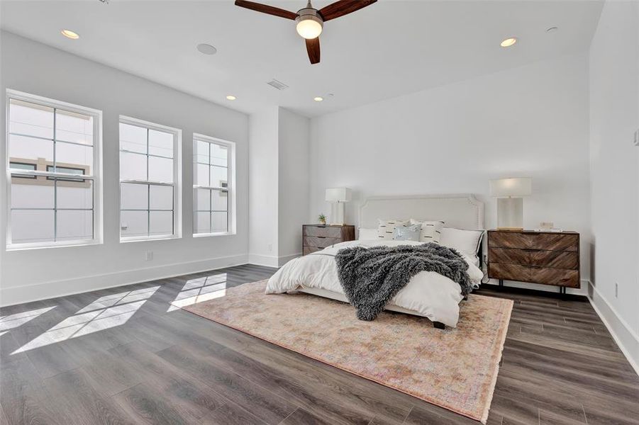 The primary bedroom is generously sized and features large windows that flood the room with abundant natural light. There's plenty of space for additional seating or furniture as well.