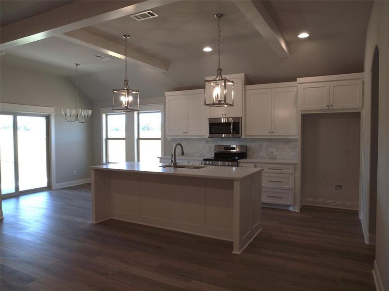 Kitchen with white cabinets, a kitchen island with sink, appliances with stainless steel finishes, and a wealth of natural light