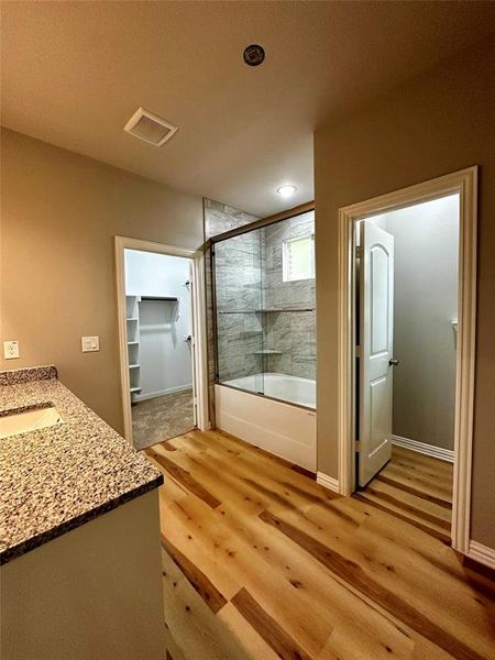 Bathroom featuring shower / bath combination with glass door, vanity, and hardwood / wood-style flooring