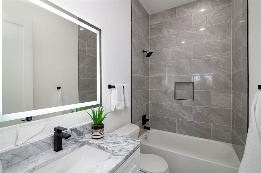 Full bathroom with vanity, toilet, and tiled shower / bath combo