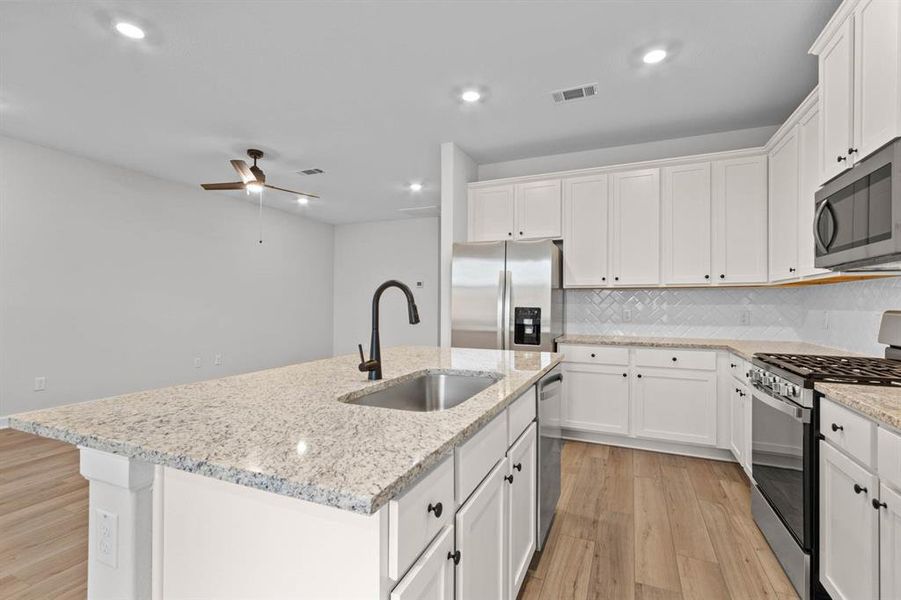 The neutral palette of white cabinets, stainless steel appliances, and granite countertops offers a versatile foundation for personalization and decor accents, allowing homeowners to easily adapt the kitchen's aesthetic to suit their individual tastes and preferences.