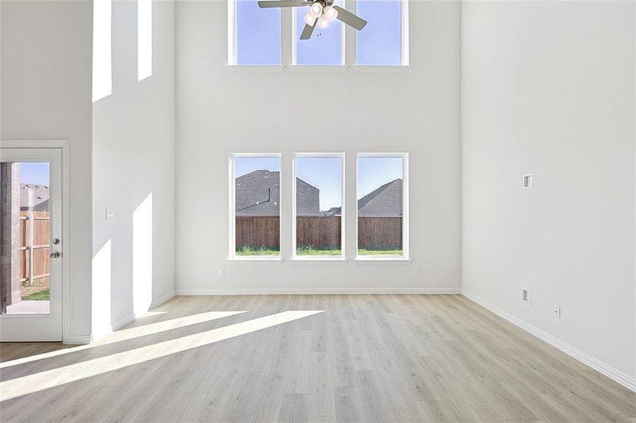 Unfurnished living room with light hardwood / wood-style floors, a high ceiling, and ceiling fan