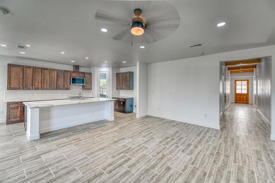 Kitchen with a breakfast bar, ceiling fan, sink, and an island with sink