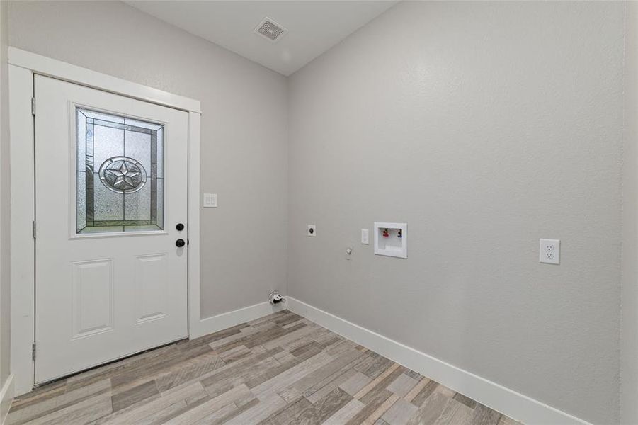 Enter the in-house utility room, equipped with convenient washer/dryer hookups and sleek tile flooring. A door leads directly to the sideyard, offering easy access for outdoor tasks and activities. There's plenty of room to install cabinets for storing all your laundry essentials, keeping everything tidy and accessible.