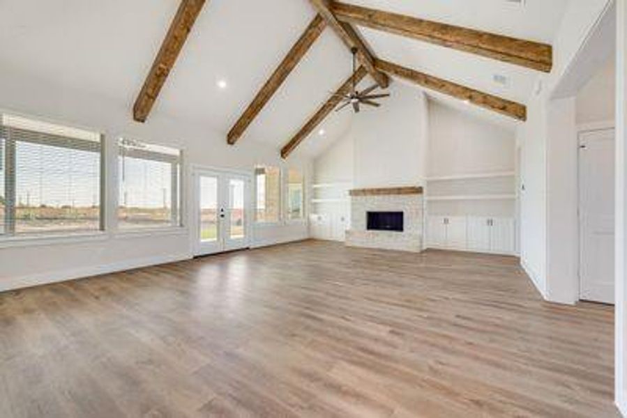 Unfurnished living room with light hardwood / wood-style floors, beam ceiling, and plenty of natural light