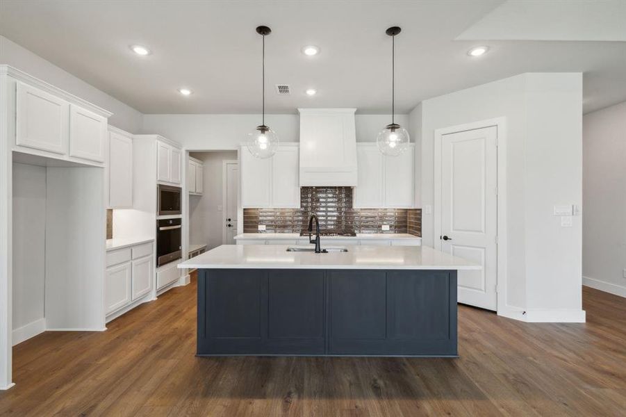 Kitchen featuring white cabinets, appliances with stainless steel finishes, dark hardwood / wood-style flooring, and an island with sink