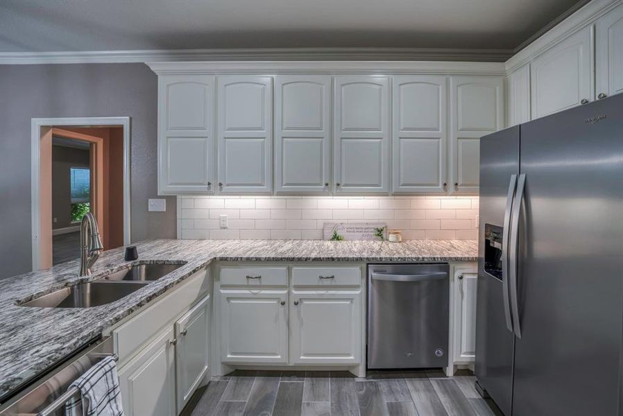 Kitchen featuring appliances with stainless steel finishes, white cabinetry, and double sink