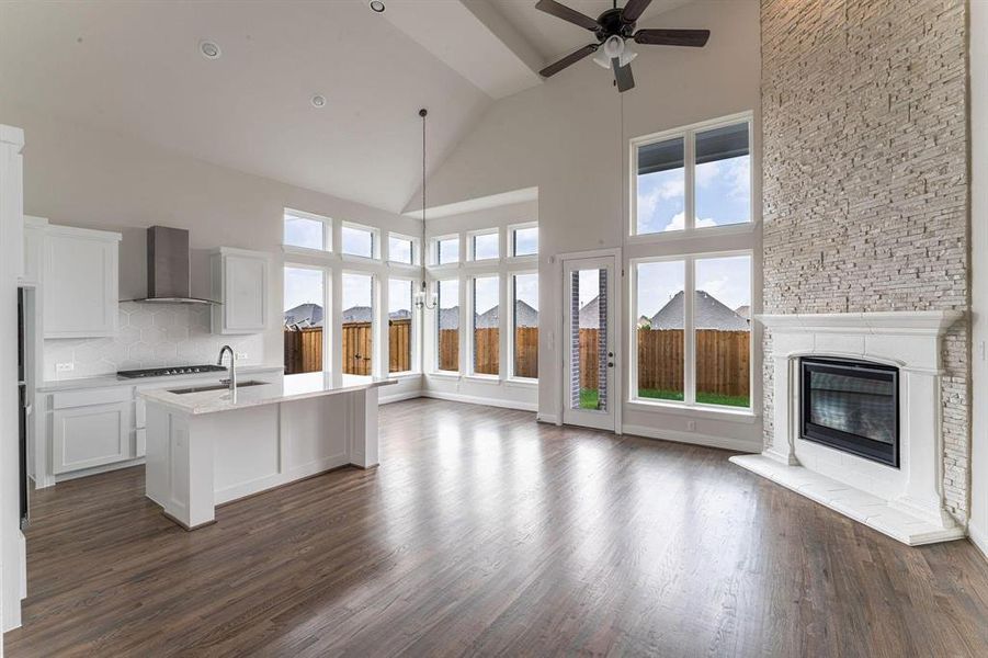 Kitchen with decorative backsplash, dark hardwood / wood-style flooring, high vaulted ceiling, and wall chimney range hood