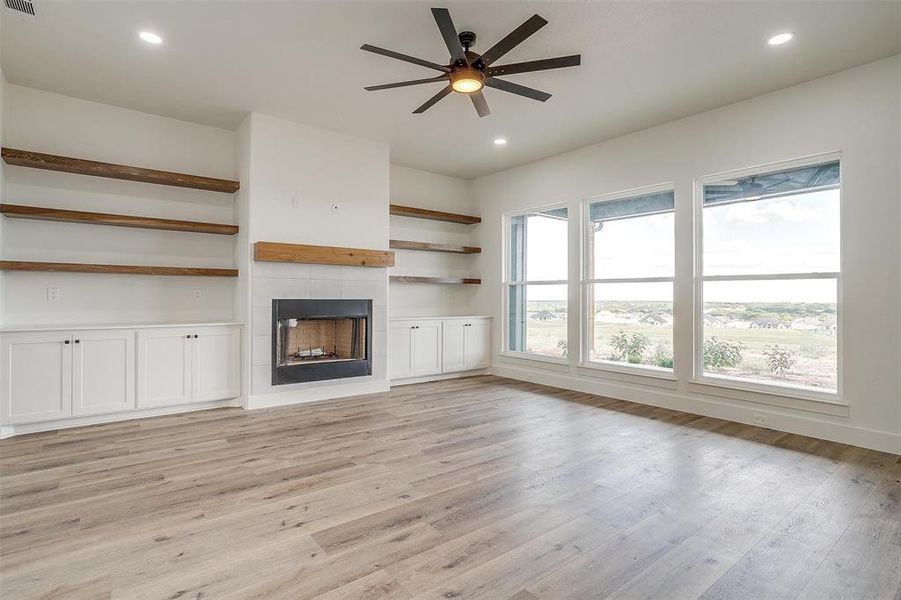 Unfurnished living room featuring ceiling fan, a fireplace, and light hardwood / wood-style floors